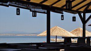 Un espace aménagé près de la plage, avec des parasols en chaume et des bancs en bois.