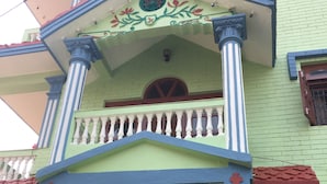 Edifici de diverses plantes amb un balcó, una entrada decorativa i una reixa de metall.