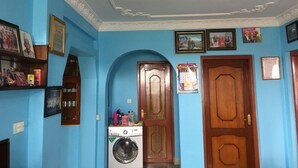 Habitació amb parets blaves, una porta de fusta, una rentadora i un ventilador al sostre.