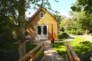 A wooden cabin with a front door, a bench, and a patio area. - Ecolodge (4-person) on the Groninger Land, near the cozy town of Groningen (Lettelbert)