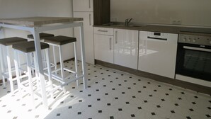 Eine Küche mit weißen Schränken, einer Arbeitsplatte, einem Spülbecken, einem Geschirrspüler und einem Herd.