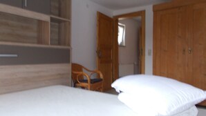 Ein Schlafzimmer mit einem Bett, einem Holzschrank und einem Sessel.