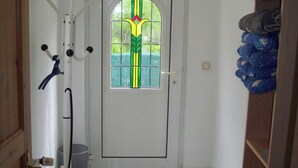 A white door with a green and yellow stained glass window, a coat rack, and a storage unit with folded items.