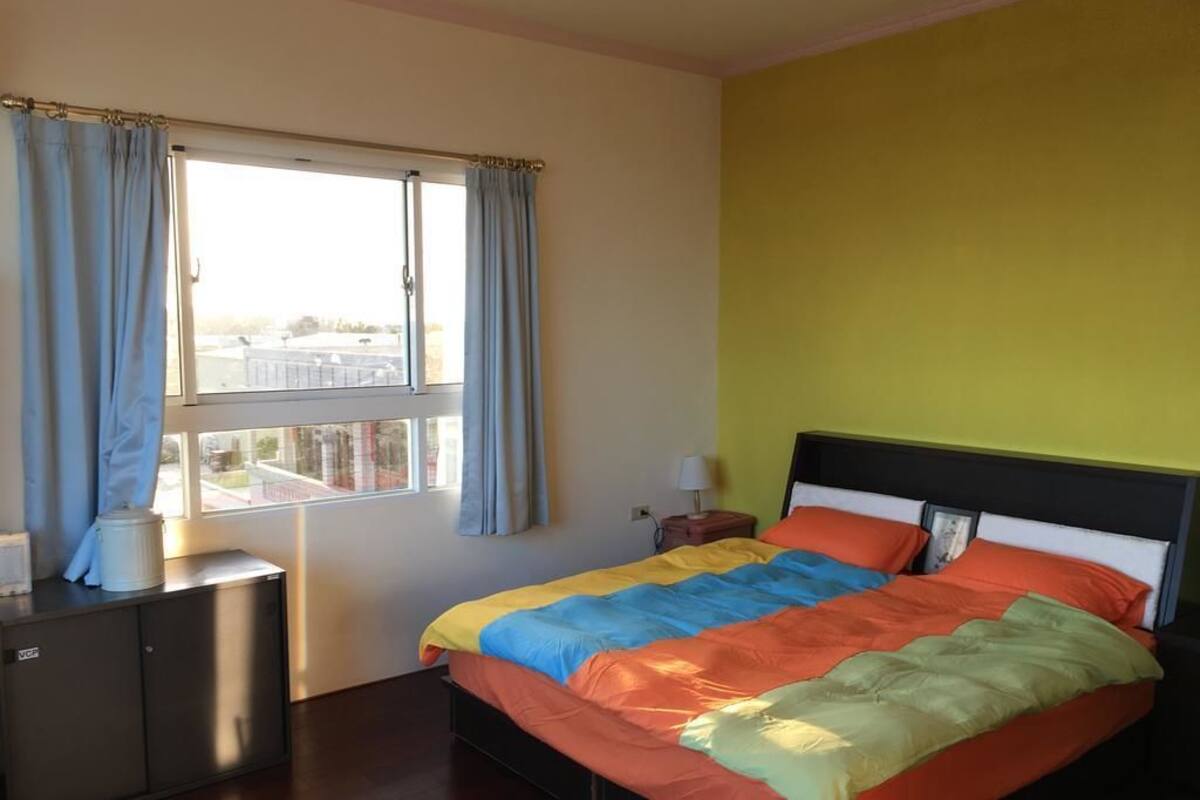 Une chambre à coucher avec un lit, une fenêtre avec des rideaux, une table de chevet et une armoire.