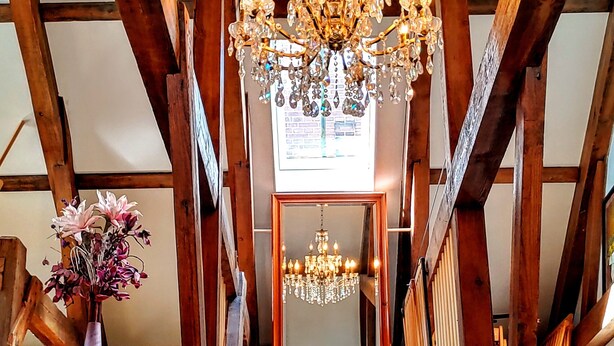 A wooden interior with a chandelier and a mirror reflecting a green view. - “Markermeerlogies am See” Historic, unique, exclusive, and very modern (Bovenkarspel)