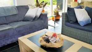 A modern living room with a grey sofa, a glass coffee table with a decorative centerpiece, and a wicker chair with cushions. - “Markermeerlogies am See” Historic, unique, exclusive, and very modern (Bovenkarspel)