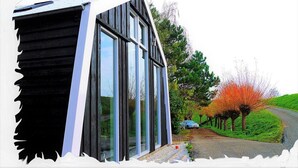 A modern building with large windows and a sloped roof. - “Markermeerlogies am See” Historic, unique, exclusive, and very modern (Bovenkarspel)
