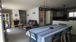 Una sala de estar con chimenea, sofá, mesa de comedor y zona de cocina.