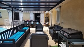Un patio exterior con piscina, mobiliario y zona de barbacoa.