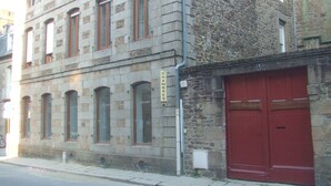 Un bâtiment en pierre doté de nombreuses fenêtres et d’une porte de garage rouge.
