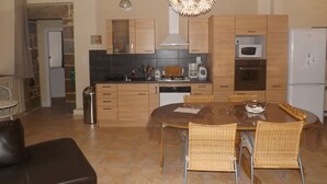 Une cuisine moderne avec des meubles en bois, une table à manger avec des chaises et un luminaire suspendu.