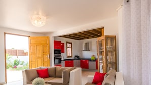 Una sala de estar moderna con un sofá grande color beige, una mesita de centro y una cocina al fondo.