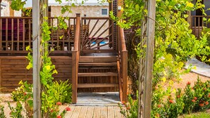 Una pérgola de madera con plantas trepadoras y una escalera de madera que lleva a una terraza.