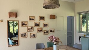 Un comedor con una mesa de madera, cuatro sillas, un florero con flores y cuadros en la pared.