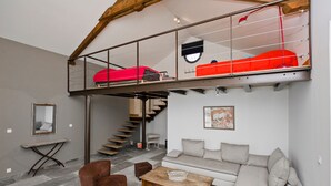 En moderne loftslejlighed med hems, trappe, sofa, sofabord og et spejl.