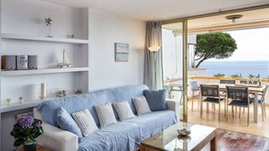 Ein modernes Wohnzimmer mit einer Couch, einem Couchtisch und Meerblick durch große Glaswände.
