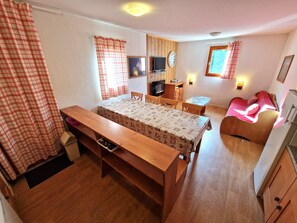 Une pièce de taille modeste comprenant un lit, un bureau, une télévision et une petite kitchenette.