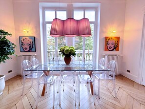 A dining area with a glass table and chairs, a potted plant, and artwork on the walls. - Paris Lyrique, 3 Br / 2 Ba, 8 ppl, 130 m² (Paris)