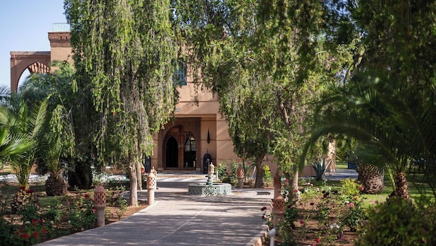 A pathway leading to a building with an arched entrance, surrounded by lush greenery and decorative lanterns. - Family villa Dar MOUDAR Marrakech - XXL pool & garden - services (Marrakech)