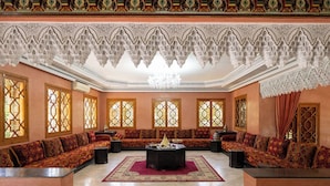 A spacious room with ornate ceiling, a central seating area, and large windows with intricate designs. - Family villa Dar MOUDAR Marrakech - XXL pool & garden - services (Marrakech)