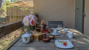 Ein Tisch im Freien mit verschiedenen Speisen, darunter Brot, Erdbeeren und eine Saftflasche.