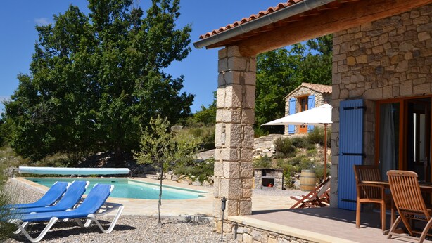 Um edifício de pedra com piscina, área de estar ao ar livre e vista para a paisagem circundante.