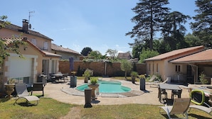 Um quintal com piscina, móveis de jardim e um muro de pedra.