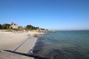 A coastal scene with a large house on a sandy beach, clear blue sky, and calm sea. - Villa indoor swimming pool, South Brittany near the sea (Fouesnant)