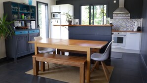 Une cuisine moderne avec une table à manger en bois, des chaises grises et un banc intégré.