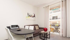 Ein modernes Wohnzimmer mit Esstisch, einer Couch, einer Mikrowelle und einem roten Apfel auf dem Tisch.