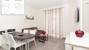 Ein modernes Wohnzimmer mit Essbereich, einer Couch, einem Fernseher und einem roten Apfel auf der Arbeitsplatte.