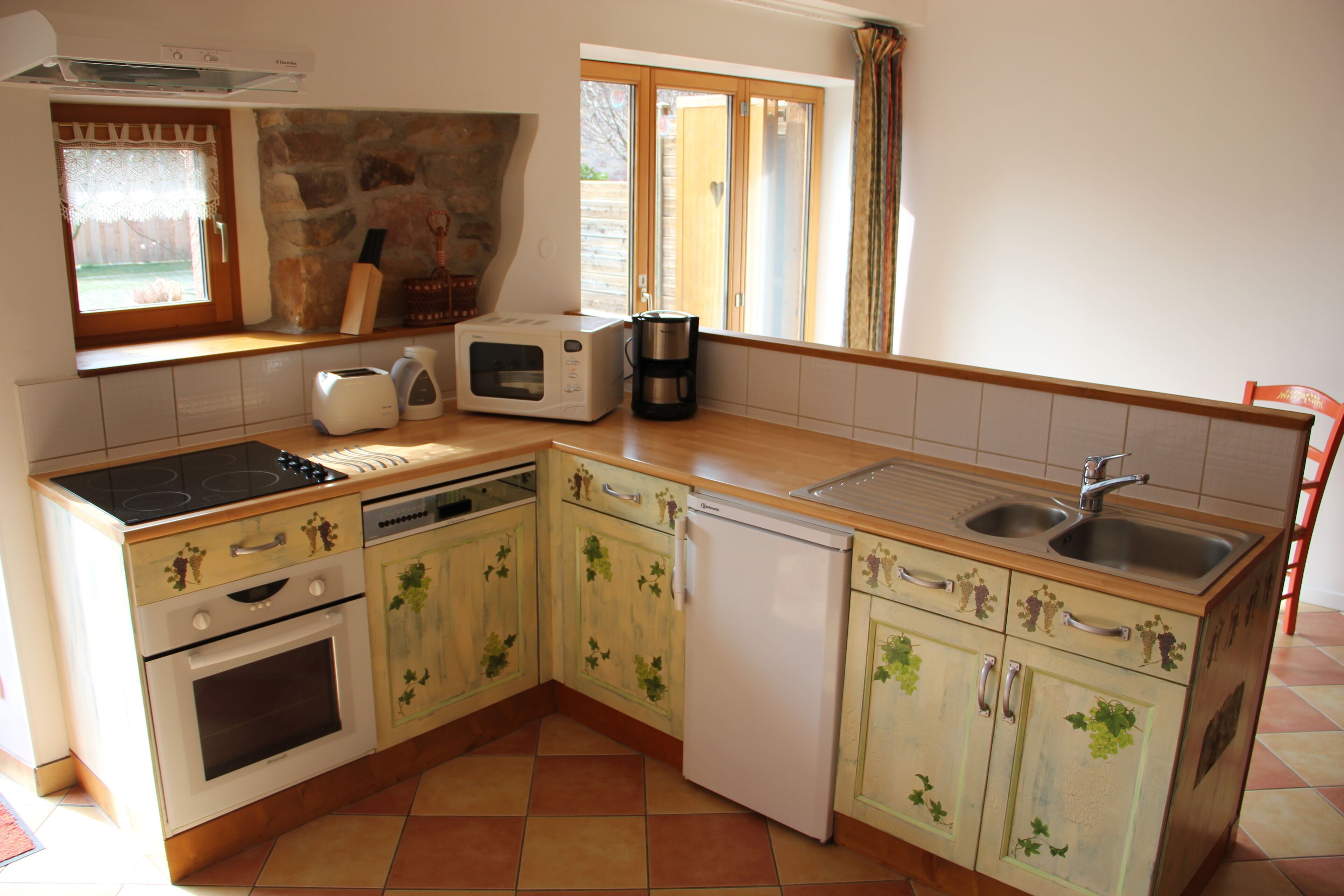 A kitchen with a stove, oven, microwave, coffee maker, and sink.