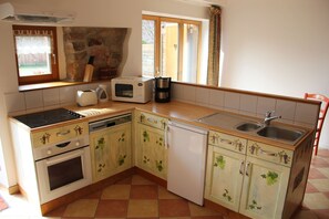 Uma cozinha equipada com fogão, forno, micro-ondas, máquina de café e pia.