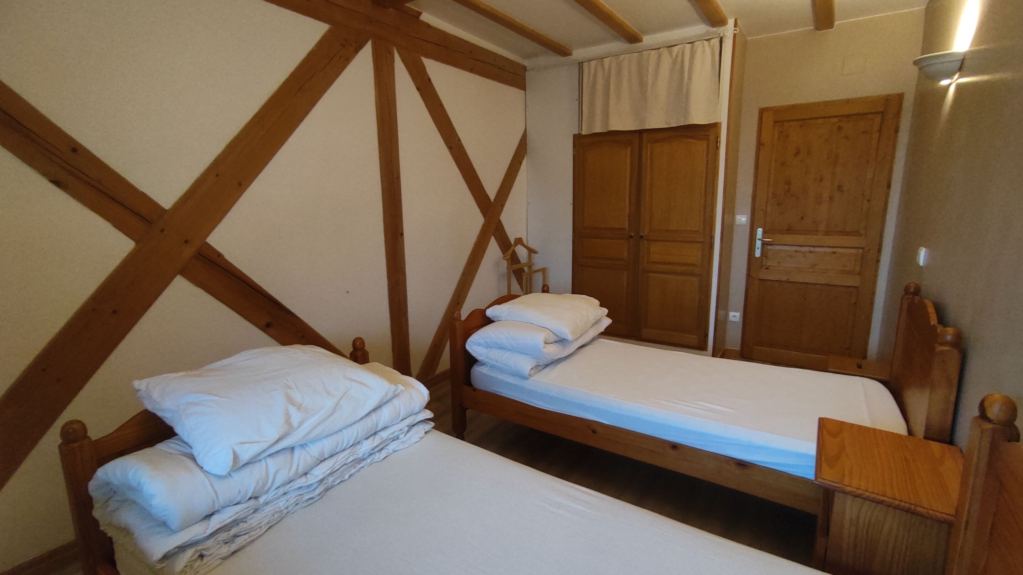 A room with two wooden bunk beds, a wooden wardrobe, and a wooden door.