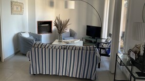 Ein Wohnzimmer mit einer Couch, einem Fernseher, einem Couchtisch und einer dekorativen Vase.