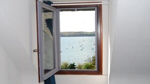 Ein Zimmer mit Fensterblick auf ein Gewässer mit Booten.