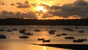 Ein Sonnenuntergang über ruhigem Wasser, mehrere Boote liegen festgemacht.