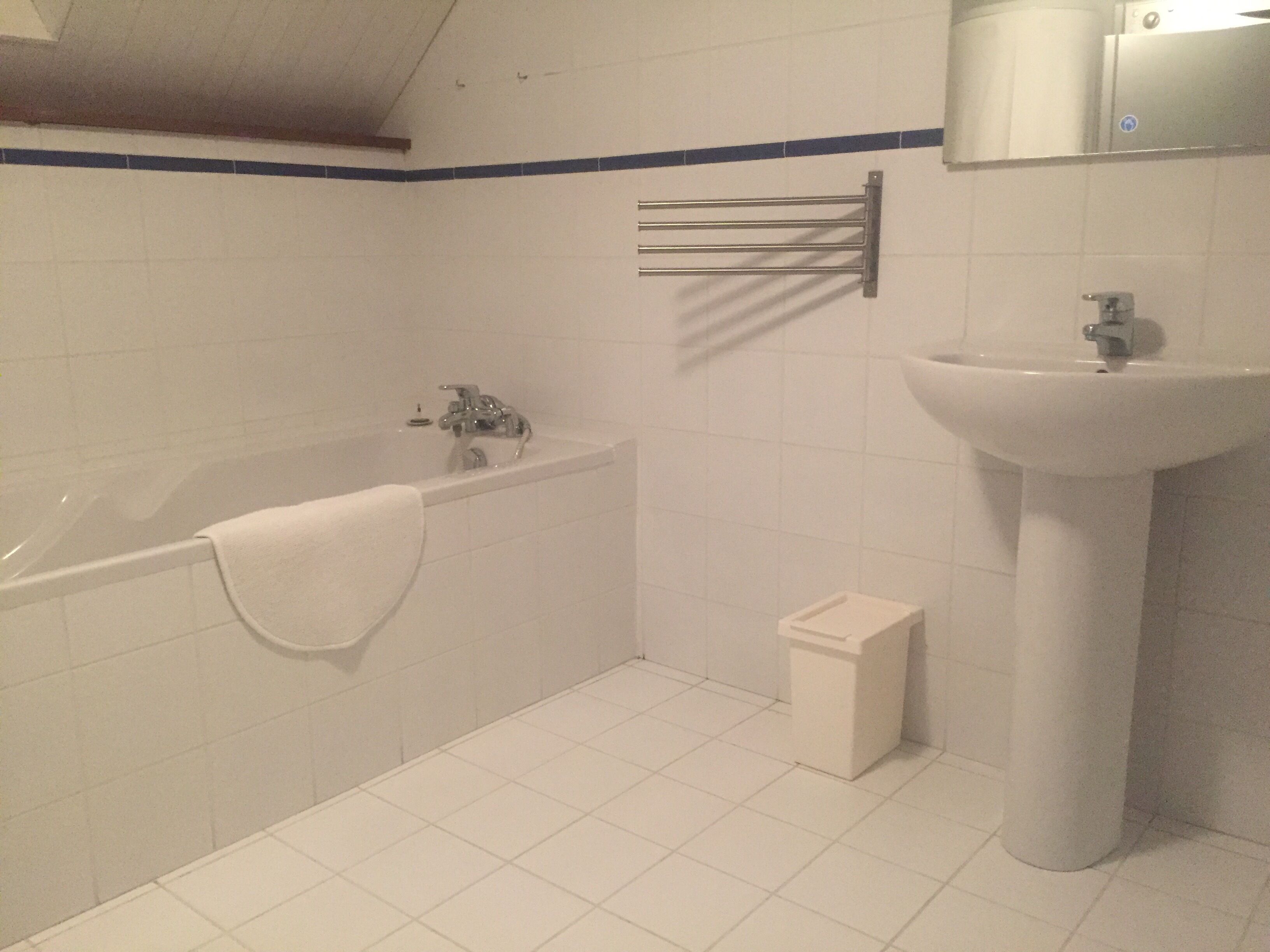 Ein Badezimmer mit Badewanne, Waschbecken und Handtuchhalter.