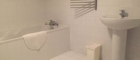 Ein Badezimmer mit Badewanne, Waschbecken und Handtuchhalter.