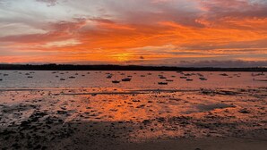Ein Strand mit Booten und einem Sonnenuntergang.