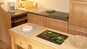 Une cuisine avec des meubles de rangement en bois, un plan de travail, une machine à café, un évier et une planche à découper.