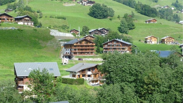 Un ensemble de chalets en bois, situés sur une colline et offrant une vue sur le paysage environnant.