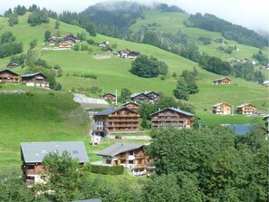 A cluster of wooden chalets on a hillside with a view of the surrounding landscape.