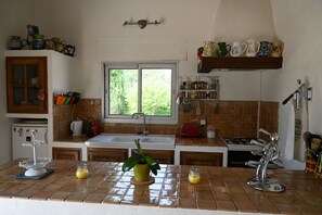 A kitchen with a window, a sink, a stove, and various kitchen utensils.