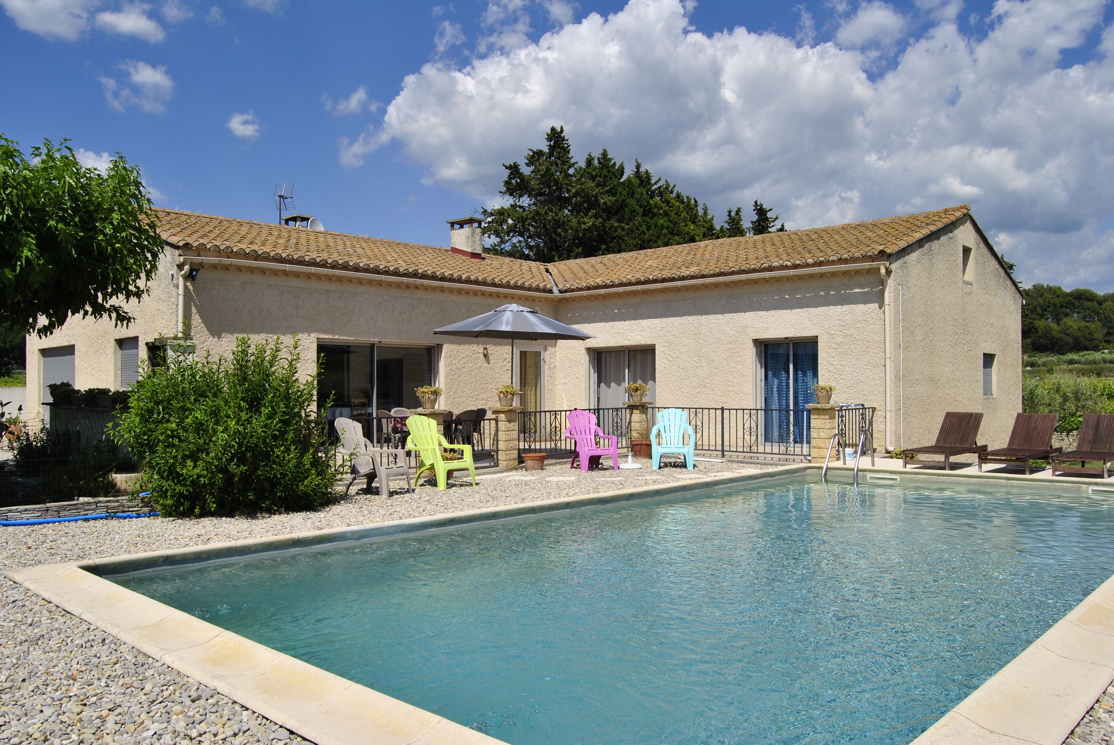 A swimming pool with lounge chairs and a building with a tiled roof.