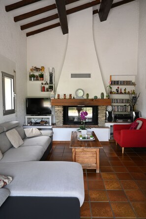 A living room with a fireplace, a television, a sofa, a red armchair, and a coffee table.