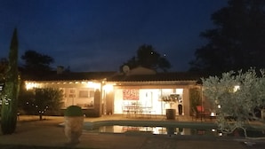 Une maison avec un patio, un coin repas et une piscine.