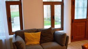 A living room with a sofa, a glass coffee table with cups and a tray, and large windows with wooden frames. - Renting a house In the heart of Amiens (Amiens)