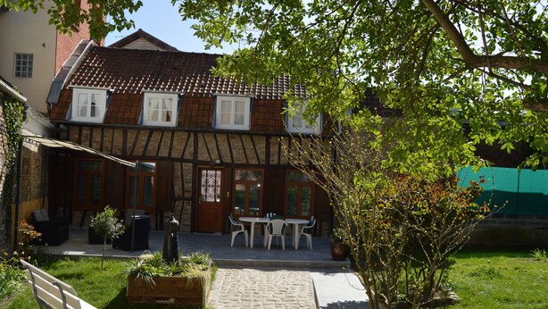 A traditional half-timbered house with a stone pathway leading to a wooden bench and a table with chairs. - Renting a house In the heart of Amiens (Amiens)