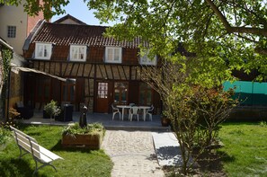 A traditional half-timbered house with a stone pathway leading to a wooden bench and a table with chairs.